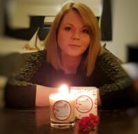Emma Fallon creator of Emma's So Naturals sitting with one of her candles 2022